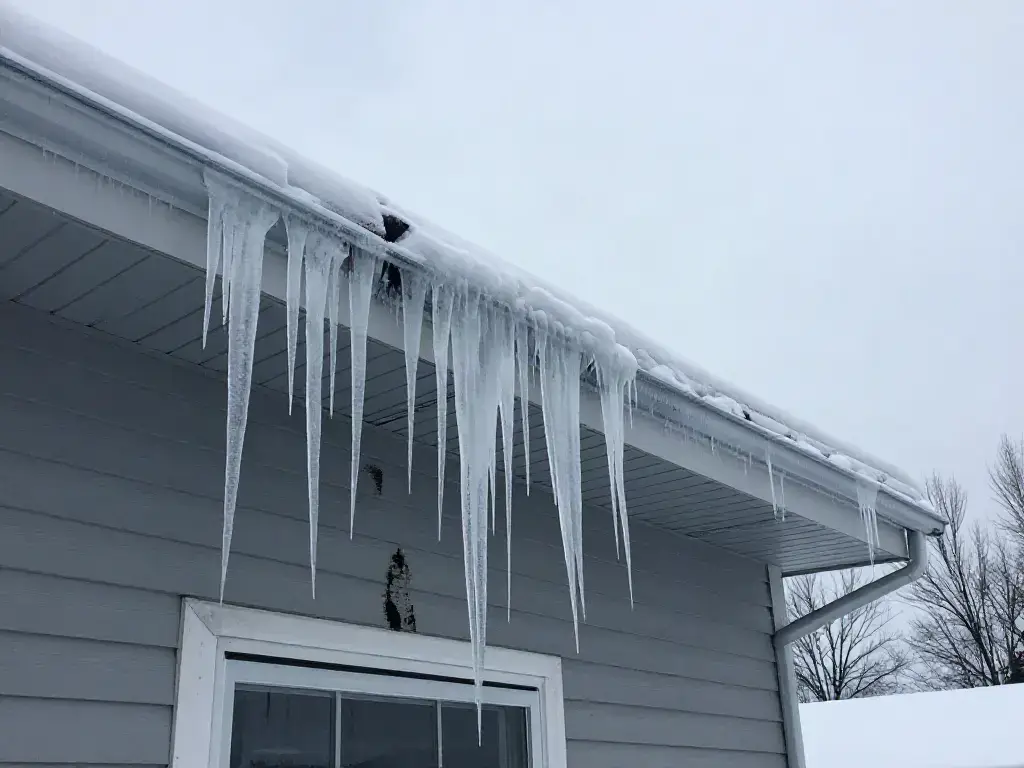 Avant : barrage de glace et longs glaçons sur la corniche d'une maison de Blainville en janvier